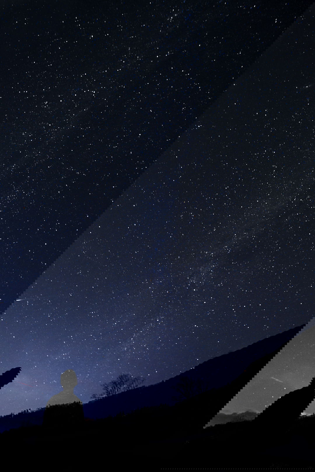 silhouette of man looking at milky way